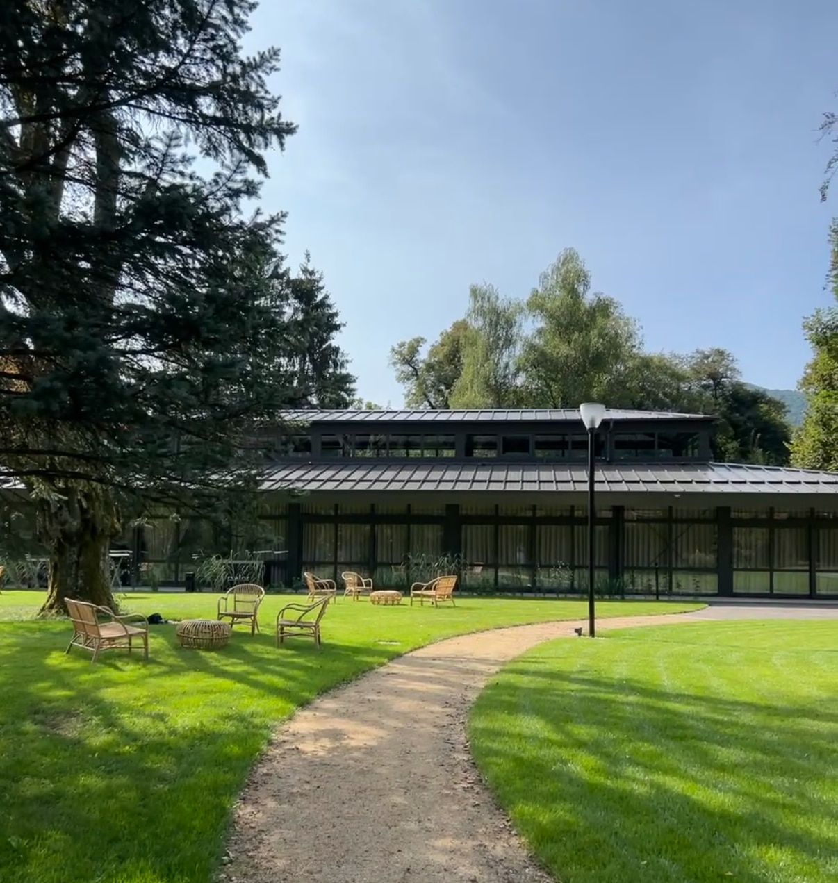 Allée en sable traversant le jardin du domaine avec vue sur le manoir et les grands arbres.