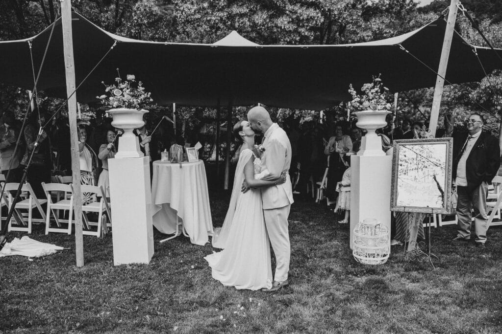 Baiser des mariés sous une tente de cérémonie durant un mariage à la Villa des Hêtres Pourpres.