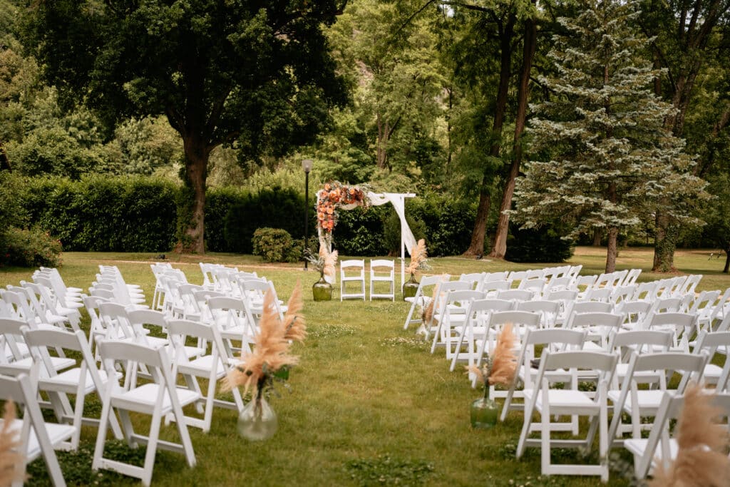 Cérémonie de mariage bohème avec arche fleurie et chaises blanches à la Villa des Hêtres Pourpres.