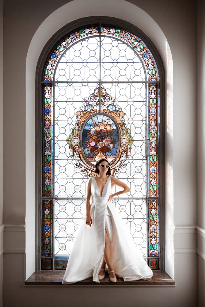 Mariée posant devant un vitrail historique de la Villa des Hêtres Pourpres.