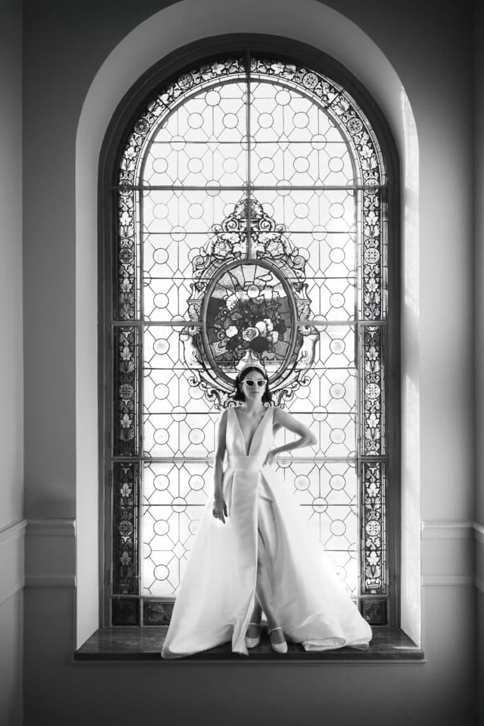 Mariée posant devant le grand vitrail en noir et blanc à la Villa des Hêtres Pourpres.