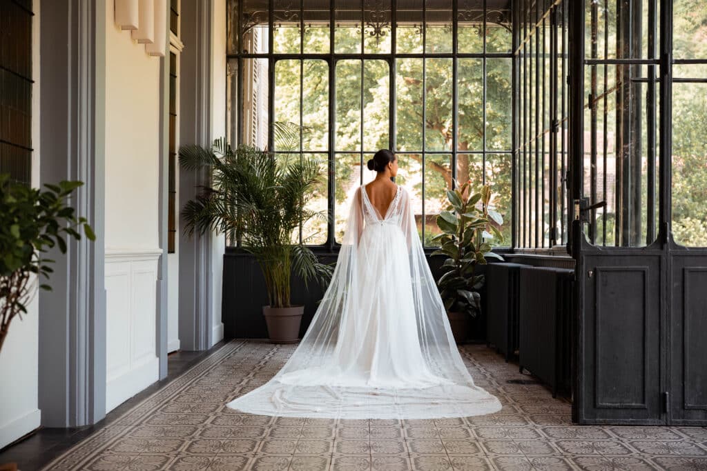 Mariée de dos dans la véranda en fer forgé de la Villa des Hêtres Pourpres.