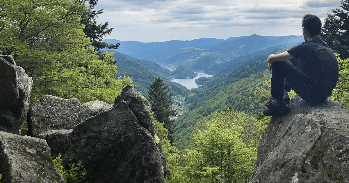 Groupe de randonneurs admirant le panorama verdoyant sur la Vallée de la Thur et les sommets des Vosges en Alsace.