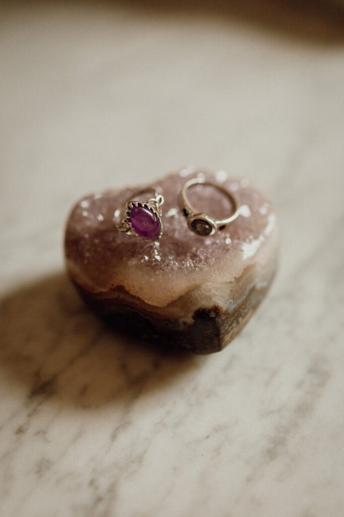 Améthyste – La villa des hêtres pourpres Donut on a marble surface with two rings resting on top—a purple gemstone ring and a plain gold band.